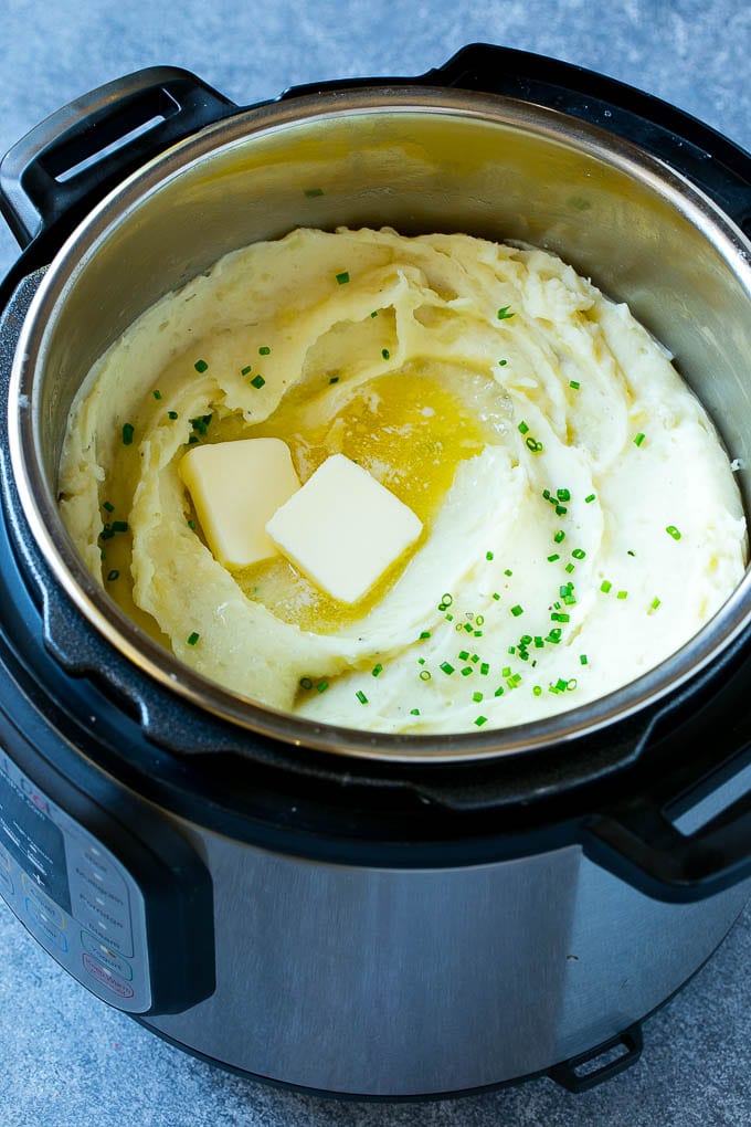 Instant Pot Mashed Potatoes Recipe | Pressure Cooker Mashed Potatoes | Easy Mashed Potatoes #potatoes #sidedish #instantpot #thanksgiving #dinner #fuyos Instant Pot mashed potatoes with butter and chives inside a pressure cooker.