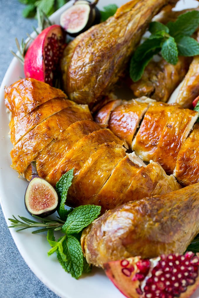 Roast Turkey Recipe | Thanksgiving Turkey | Holiday Turkey | Baked Turkey #turkey #thanksgiving #christmas #dinner #glutenfree #fuyos Sliced roast turkey on a serving platter with rosemary, pomegranate and figs.