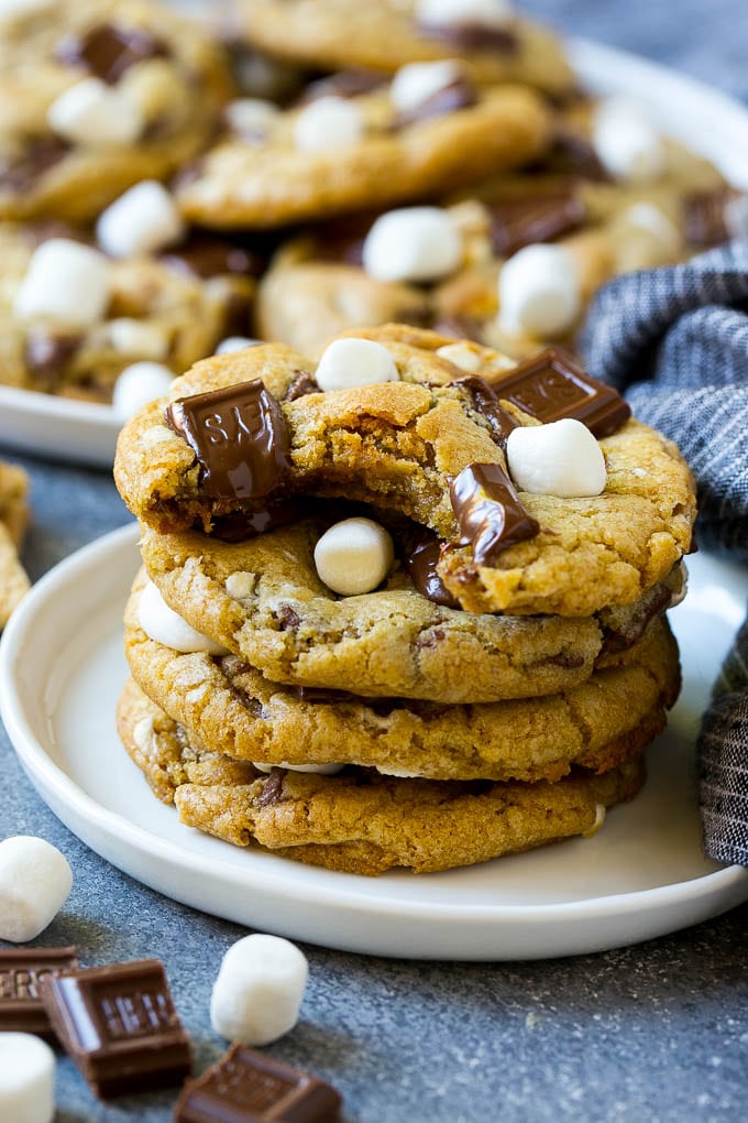 S'mores Cookies Recipe | Marshmallow Cookies #smores #marshmallow #chocolate #cookies #dessert #fuyos A stack of S'mores cookies with a bite taken out of one.