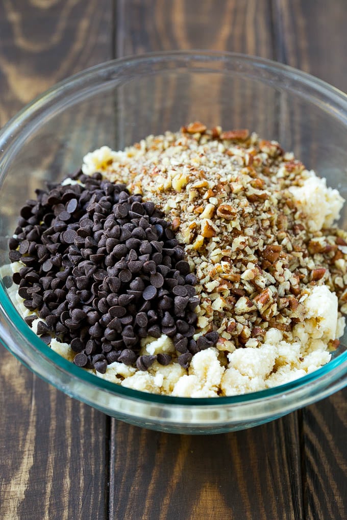Snowball Cookies Recipe | Mexican Wedding Cookies | Russian Tea Cakes #cookies #pecan #chocolate #baking #dessert #christmas #fuyos A bowl of dough topped with miniature chocolate chips and chopped pecans.