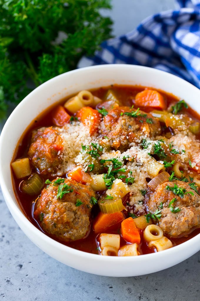 Italian Meatball Soup Recipe | Meatball Soup | Beef Meatballs #meatballs #beef #soup #italian #dinner #fuyos #comfortfood A bowl of meatball soup topped with chopped parsley and grated cheese.