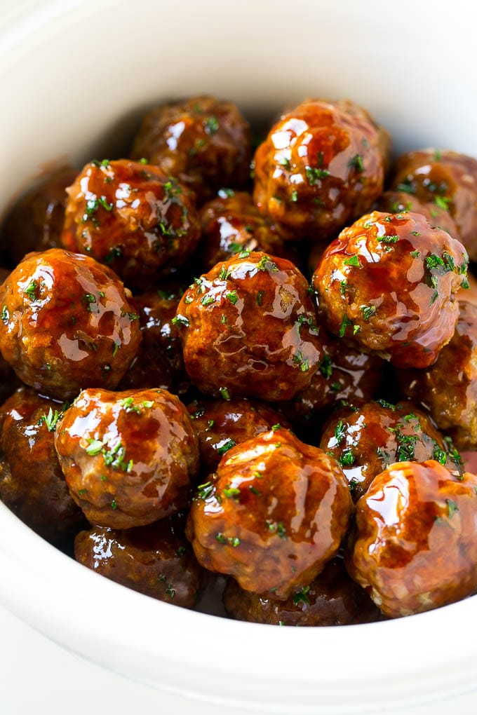 Sweet and Sour Meatballs Recipe | Slow Cooker Meatballs | Crockpot Meatballs | Cocktail Meatballs #meatballs #beef #slowcooker #crockpot #dinner #appetizer #fuyos Sweet and sour meatballs garnished with parsley in a slow cooker.
