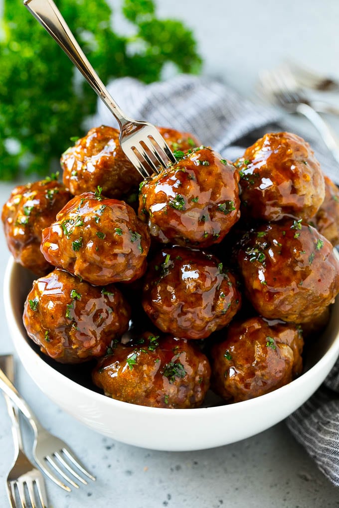 Sweet and Sour Meatballs Recipe | Slow Cooker Meatballs | Crockpot Meatballs | Cocktail Meatballs #meatballs #beef #slowcooker #crockpot #dinner #appetizer #fuyos A bowl of sweet and sour meatballs with a cocktail fork in it.