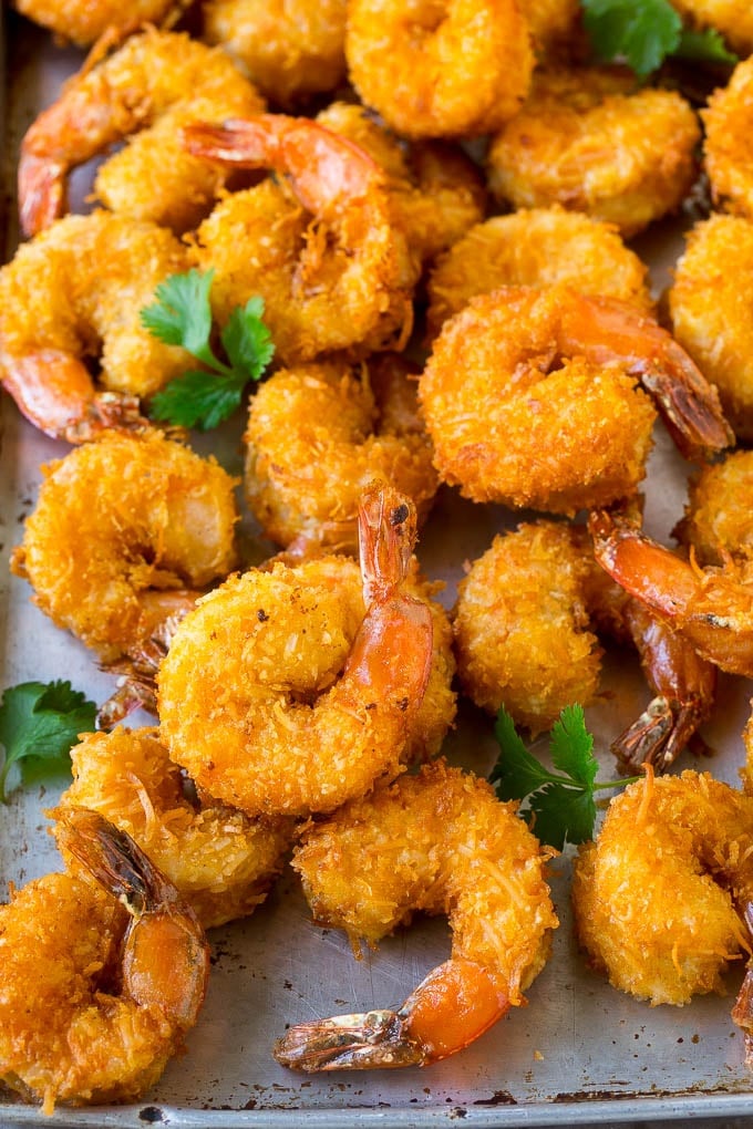 Coconut Shrimp Recipe | Fried Shrimp | Shrimp Appetizer #shrimp #coconut #appetizer #seafood #dinner #fuyos A pile of crispy coconut shrimp on a sheet pan with cilantro leaves for garnish.