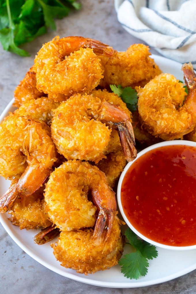 Coconut Shrimp Recipe | Fried Shrimp | Shrimp Appetizer #shrimp #coconut #appetizer #seafood #dinner #fuyos A plate of coconut shrimp with a bowl of sweet chili sauce.