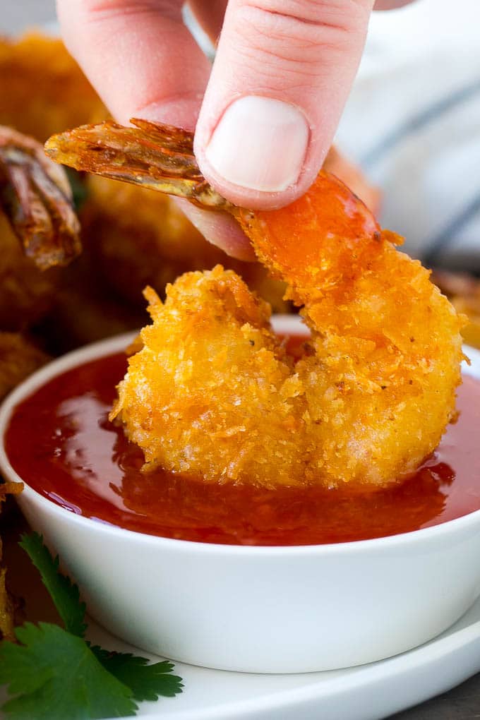 Coconut Shrimp Recipe | Fried Shrimp | Shrimp Appetizer #shrimp #coconut #appetizer #seafood #dinner #fuyos A hand dipping a crispy prawn into a bowl of sweet chili sauce.