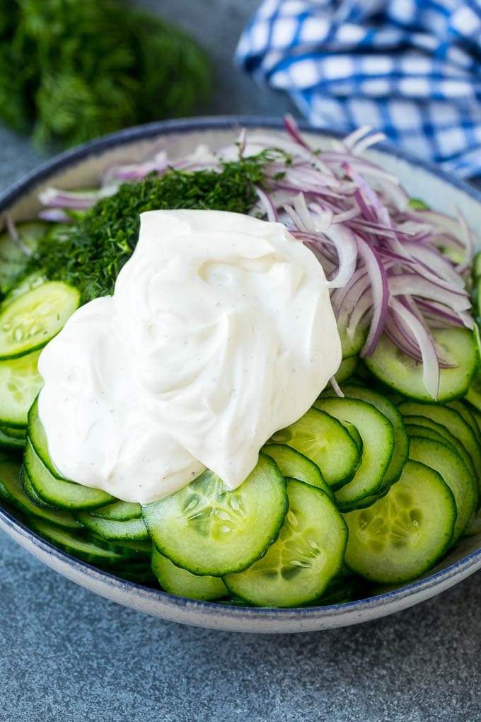 Creamy Cucumber Salad Recipe | German Cucumber Salad | Cucumber Salad #cucumber #salad #dinner #lunch #fuyos #cucumbersalad Cucumbers, red onion and dill in a bowl topped with creamy dressing.