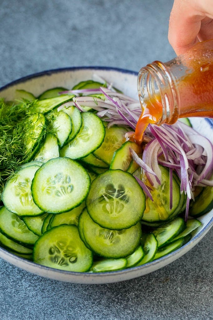 Cucumber Salad Recipe | Cucumber Dill Salad | Cucumber Recipe #cucumbers #salad #glutenfree #sidedish #fuyos Dressing being poured over sliced vegetables and fresh dill.