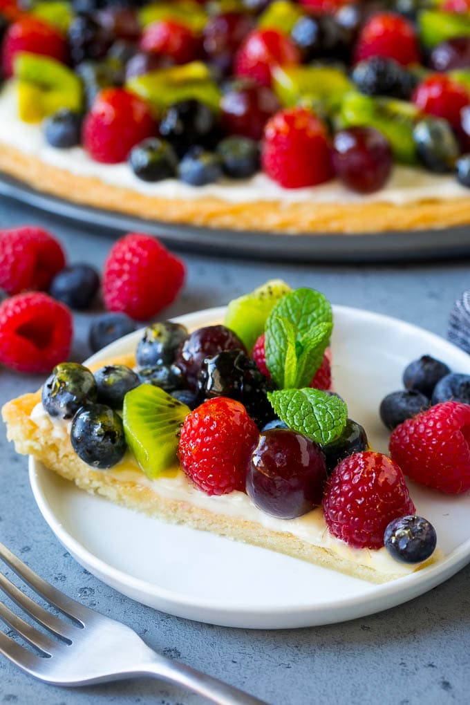 Fruit Pizza Recipe | Dessert Pizza | Fruit Dessert #cookie #fruit #pizza #dessert #sweets #fuyos A slice of fruit pizza topped with cream cheese frosting and berries.