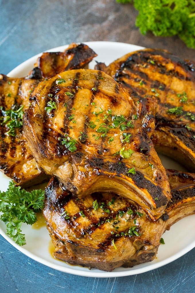 Pork Chop Marinade Recipe | Marinated Pork Chops | Grilled Pork Chops #pork #porkchops #grilling #dinner #fuyos Pork chop marinade on grilled pork chops. The pork chops are on a serving plate garnished with parsley.