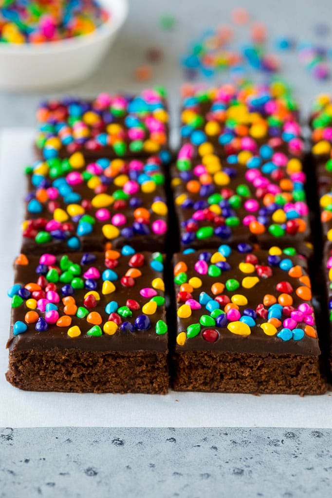 Cosmic Brownies Recipe | Cocoa Brownies | Frosted Brownies #brownies #chocolate #dessert #fuyos #sprinkles Cosmic brownies topped with chocolate fudge and crunchy rainbow sprinkles.
