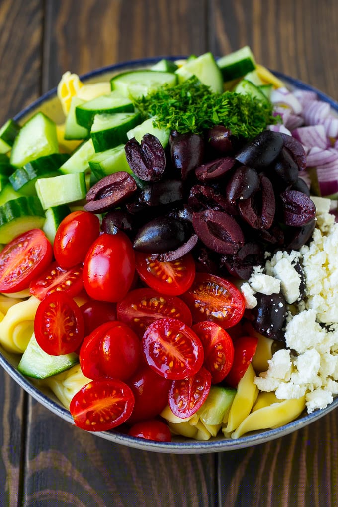 Greek Tortellini Salad Recipe | Pasta Salad | Tortellini Salad | Greek Salad #greek #tortellini #pasta #salad #cucumbers #olives #dinner #fuyos Tortellini in a bowl topped with olives, tomatoes, cucumber and feta cheese.