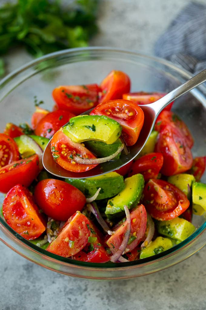 A serving spoon of veggies in a lime dressing.