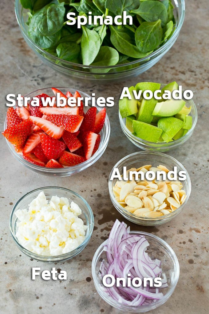 Bowls of ingredients like feta cheese, almonds, red onion and avocado.