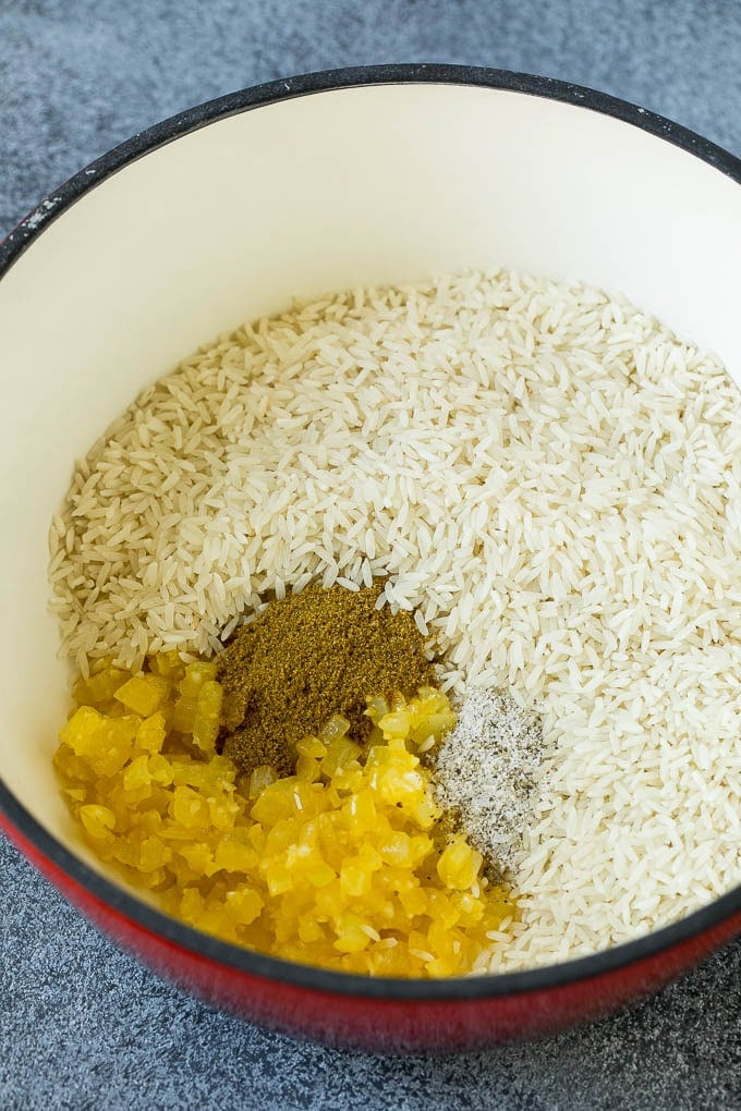 Onions, garlic, white rice and spices in a pot.