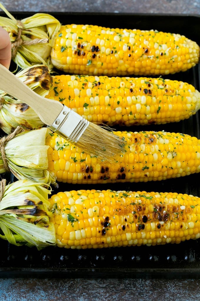 Cobs being brushed with herb butter.