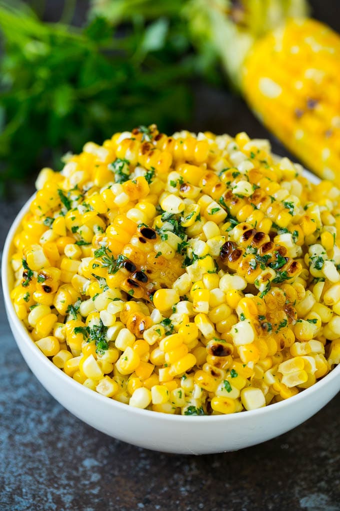 Grilled corn cut off the cob with herb butter in a bowl.
