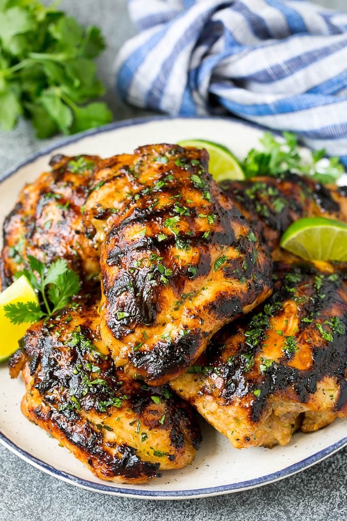 Grilled Chicken Thighs Recipe | Marinated Chicken Thighs #chicken #grilling #marinade #dinner #cilantro #lime #fuyos Grilled chicken thighs with a garnish of cilantro and lime wedges.