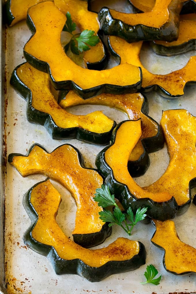 Roasted Acorn Squash | Acorn Squash Recipe #squash #winter #sidedish #dinner #fuyos Sliced of cinnamon roasted acorn squash on a sheet pan.
