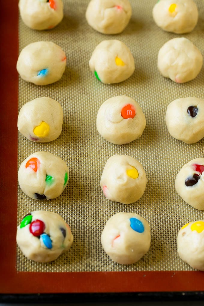 M&M Cookies Recipe #cookies #chocolate #baking #dessert #sweets #fuyos Balls of cookie dough on a baking sheet.