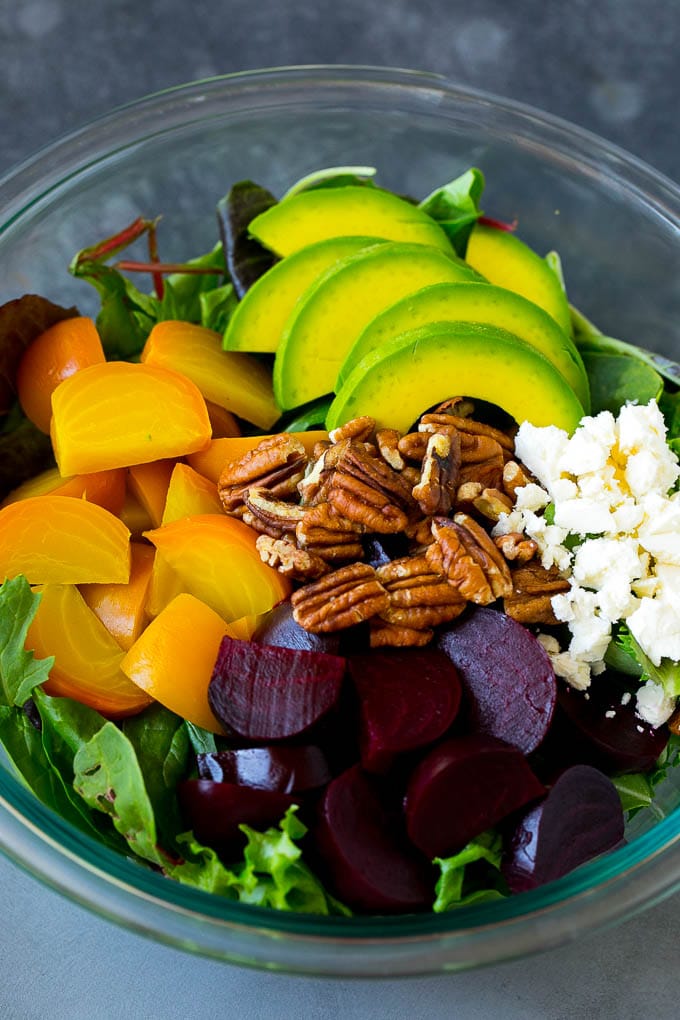Beet Salad Recipe #beets #avocado #feta #salad #dinner #fuyos Red and yellow beets, salad greens, feta cheese, avocado and pecans in a bowl.