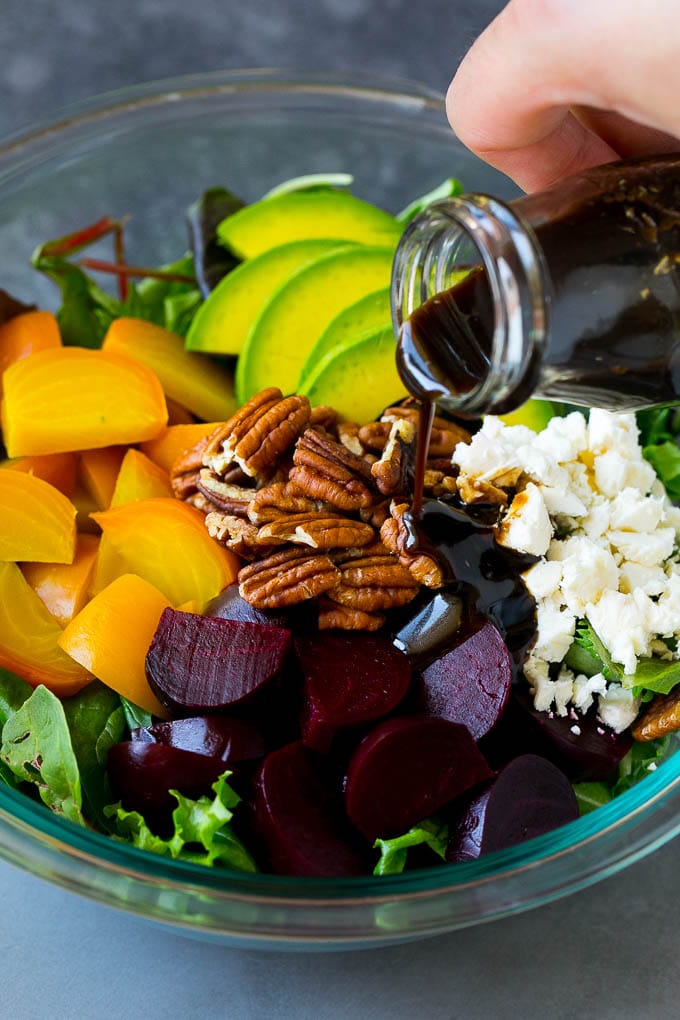 Beet Salad Recipe #beets #avocado #feta #salad #dinner #fuyos Balsamic dressing being poured over beets, sliced avocado and feta cheese.