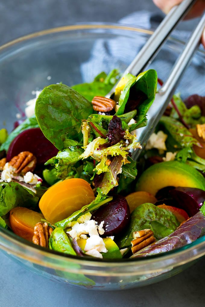 Beet Salad Recipe #beets #avocado #feta #salad #dinner #fuyos Tongs serving a portion of beet salad tossed in balsamic dressing.