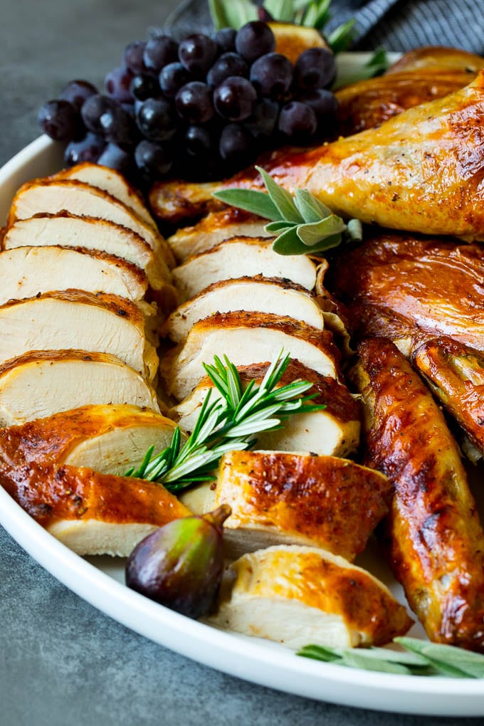 Sliced spatchcock turkey on a serving platter garnished with herbs.