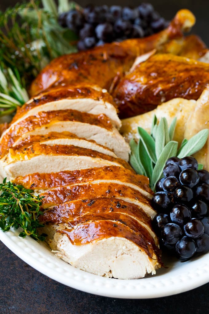 Thanksgiving Turkey Recipe | Roasted Turkey #turkey #thanksgiving #fall #dinner #fuyos Sliced Thanksgiving turkey on a serving platter with fresh herbs.