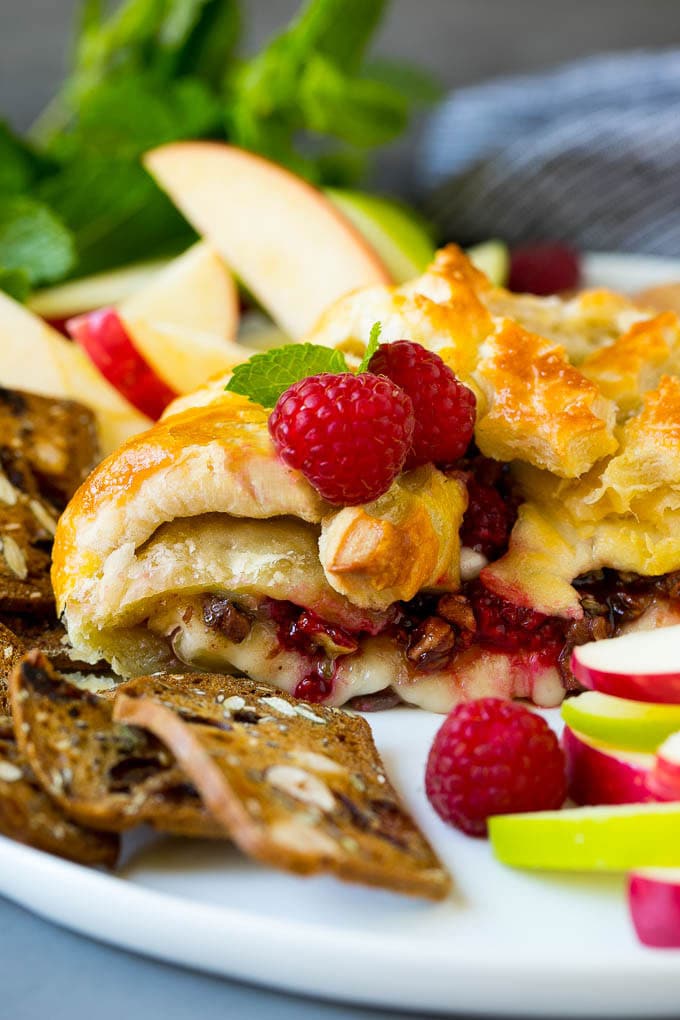 Baked Brie Recipe | Pastry Wrapped Brie #brie #cheese #appetizer #pecans #raspberries #fuyos A cross section of baked brie filled with raspberries and pecans.