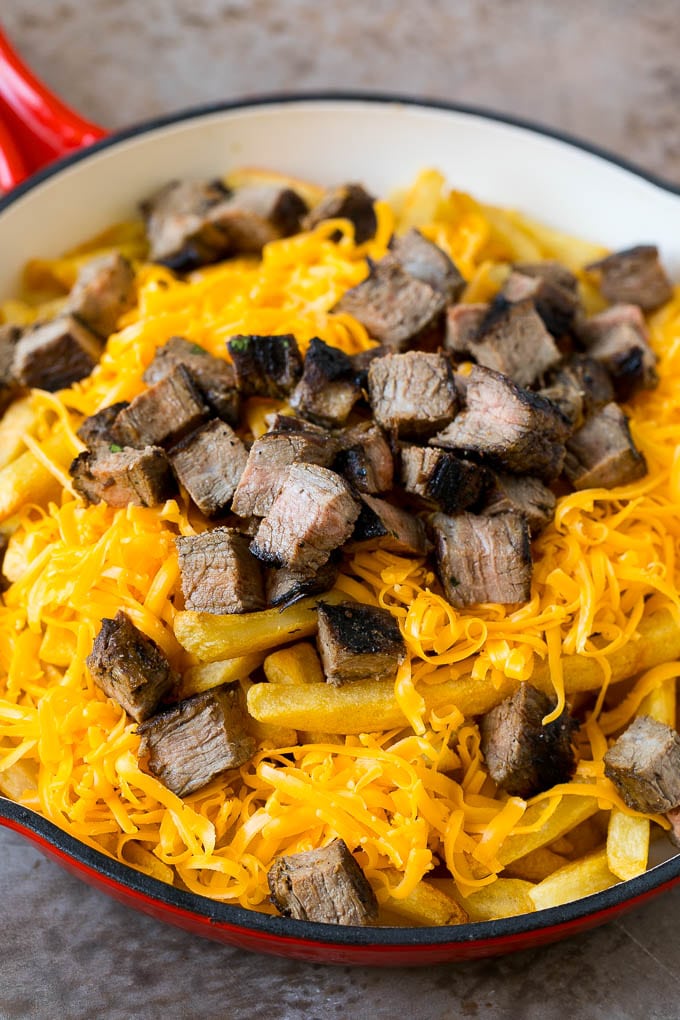 Carne Asada Fries Recipe | Steak Fries #fries #frenchfries #steak #salsa #avocado #cheese #dinner #appetizer #fuyos French fries topped with shredded cheese and diced steak.