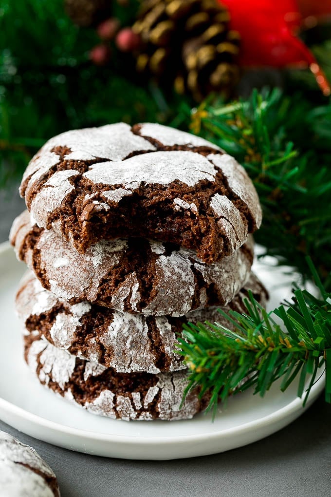 Chocolate Crinkle Cookies Recipe #cookies #chocolate #christmas #dessert #baking #fuyos A stack of chocolate crinkle cookies with a bite taken out of one.