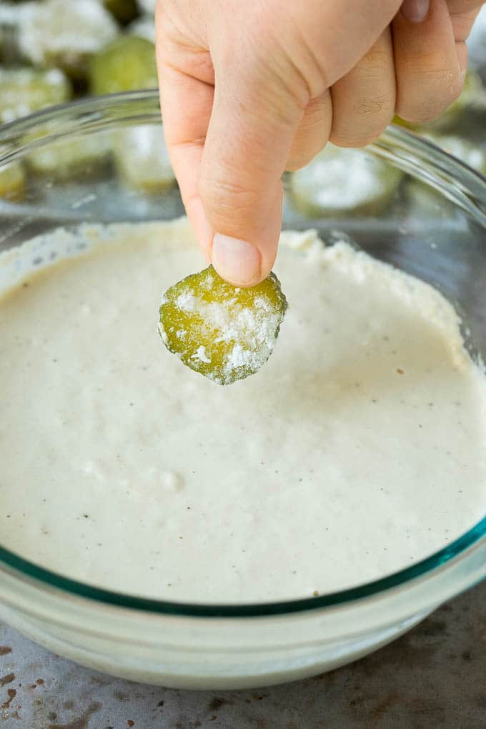Fried Pickles Recipe #pickles #appetizer #snack #fuyos A slice being dipped into a bowl of beer batter.