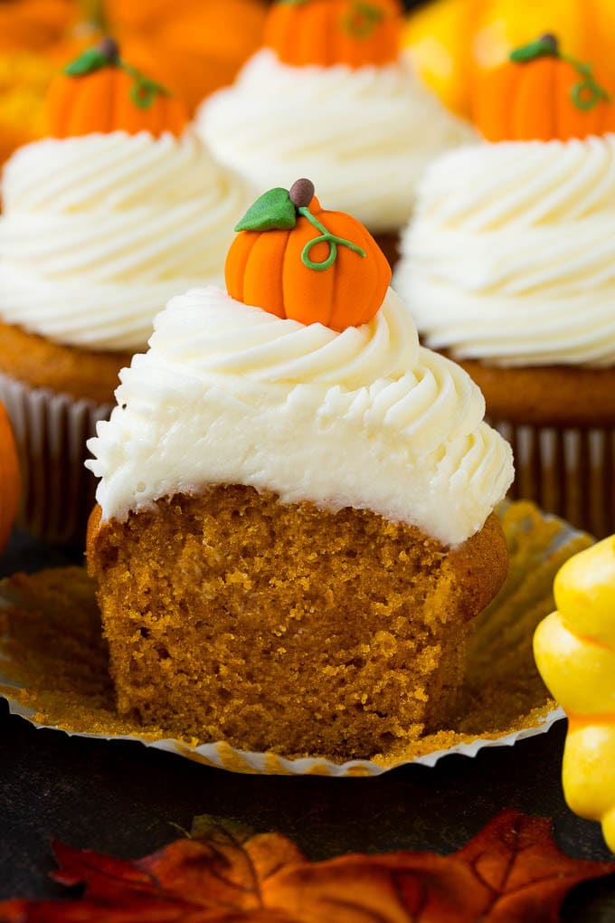 A pumpkin cupcake cut in half, surrounded by fall decorations.