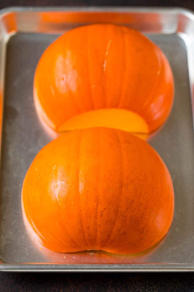 Pumpkin Puree Recipe #pumpkin #baking #fall #thanksgiving #fuyos A pumpkin cut in half on a sheet pan.