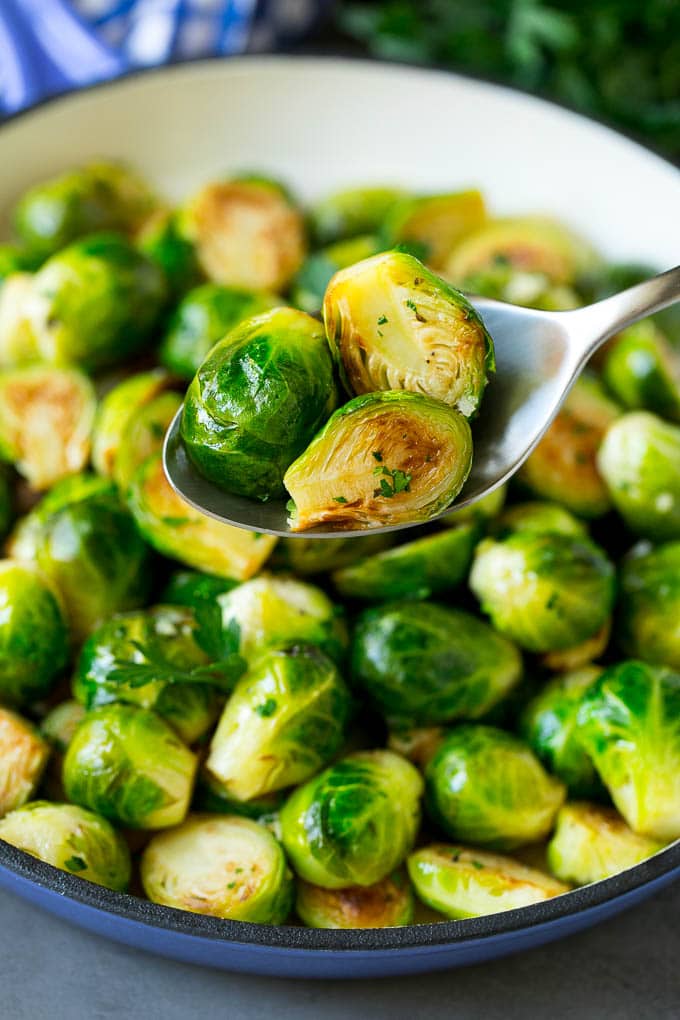Sauteed Brussels Sprouts Recipe | Brussels Sprouts Side Dish #brusselssprouts #sprouts #veggies #sidedish #garlic #vegetarian #dinner #fuyos A spoon holding up a serving of cooked brussels sprouts.