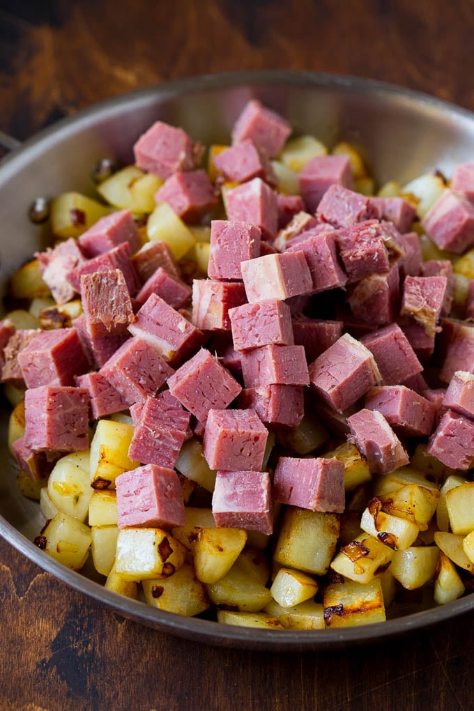 Corned Beef Hash Recipe #hash #cornedbeef #stpatricksday #breakfast #brunch #potatoes #fuyos Cubed corn beef on top of cooked potatoes.