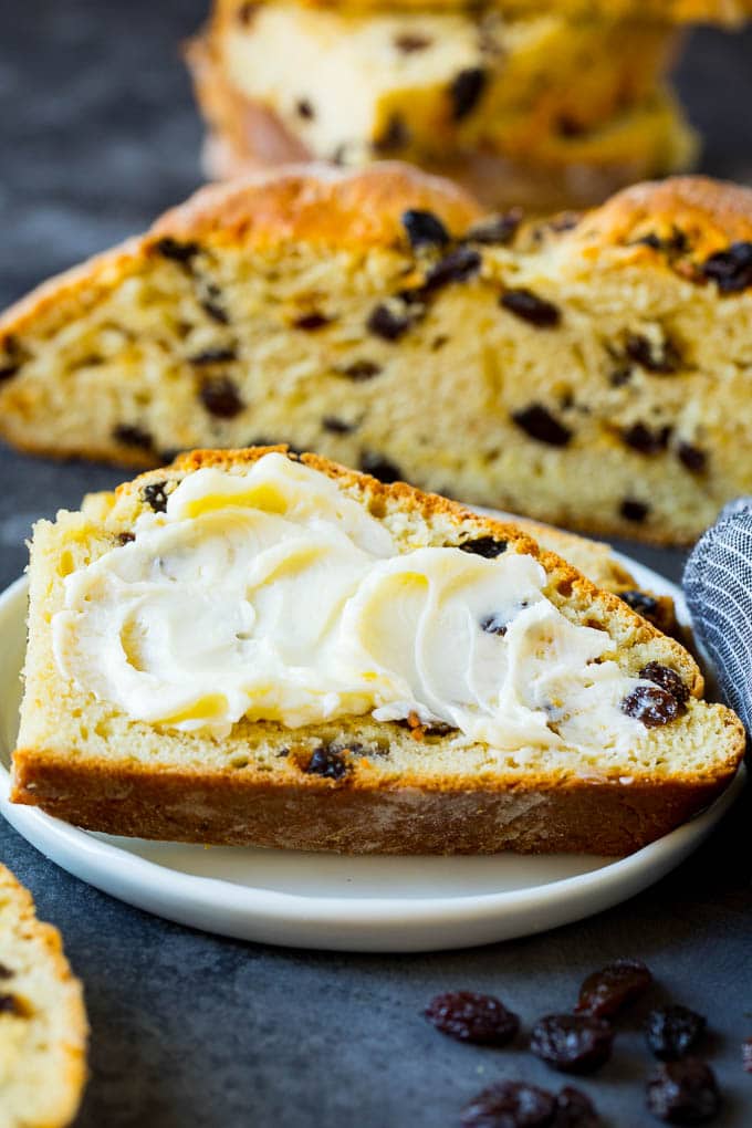 Irish Soda Bread Recipe #bread #baking #stpatricksday #sidedish #fuyos A slice of Irish soda bread with butter spread on it.