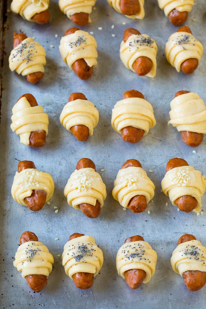 Mini hot dogs wrapped in crescent dough and topped with seeds.