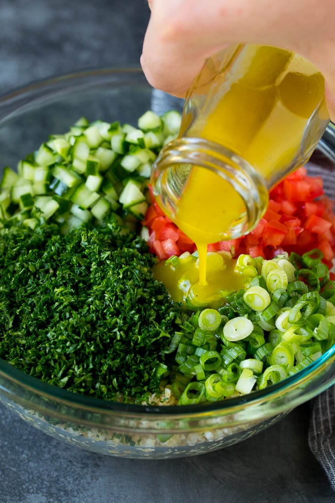 Tabbouleh Salad | Tabouli #salad #wheat #tomatoes #cucumber #healthy #sidedish #dinner #fuyos Dressing being poured into a bowl of bulgur wheat salad.