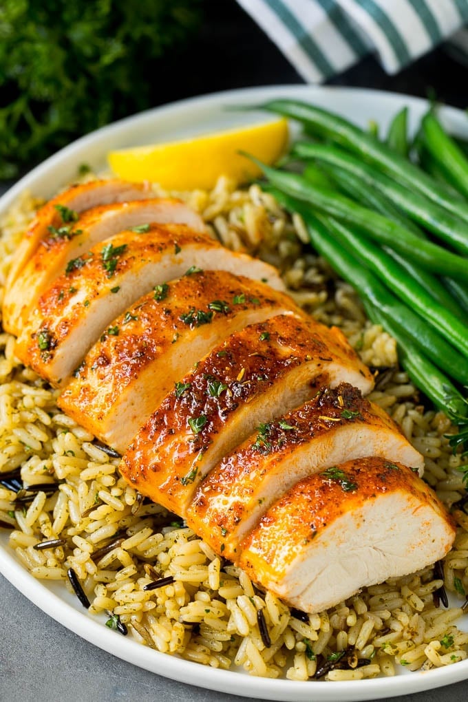 Baked chicken breast served with rice and green beans.