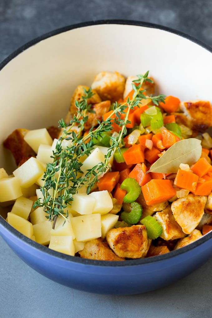Ingredients such as vegetables, potatoes and herbs in a pot.