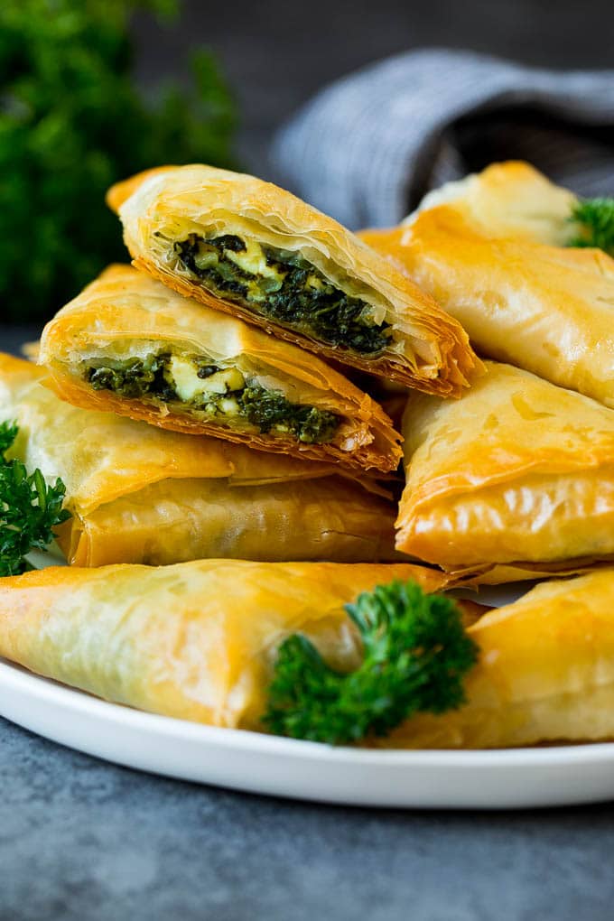 Spanakopita Recipe #appetizer #snack #spinach #cheese #fuyos A plate of spanakopita with two cut in half.