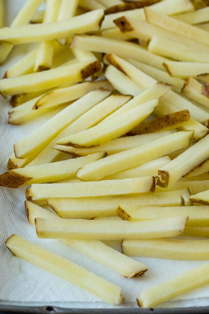 Homemade French Fries Recipe #potatoes #fries #dinner #fuyos Potatoes cut into fry shapes on a paper towel lined pan.