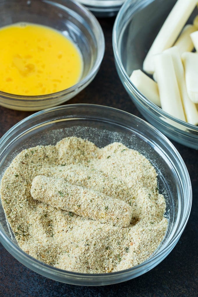 Mozzarella Sticks Recipe #cheese #appetizer #fuyos Cheese in a bowl of seasoned breadcrumbs.