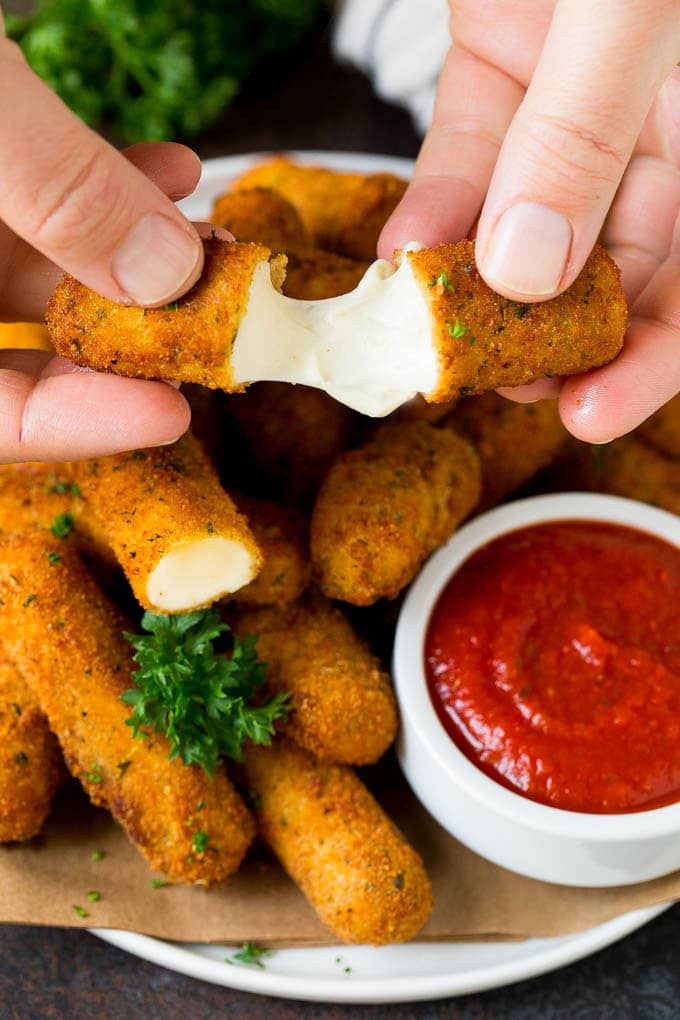 Mozzarella Sticks Recipe #cheese #appetizer #fuyos A hand pulling apart mozzarella sticks.