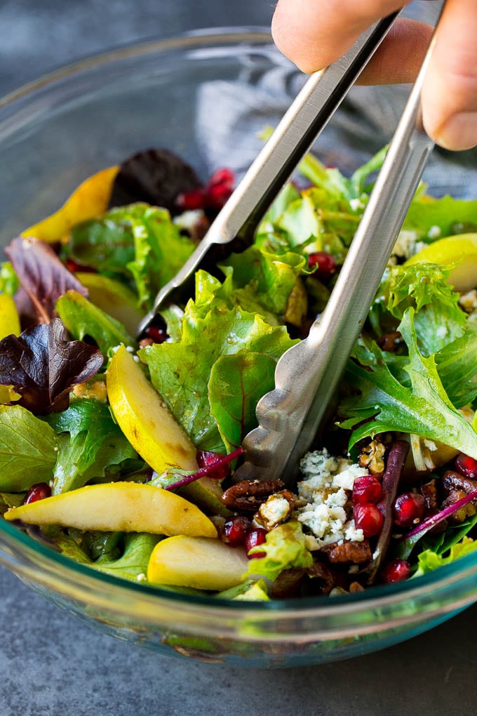 Pear Salad Recipe #salad #pears #fall #winter #dinner #fuyos Tongs serving up a portion of pear salad.