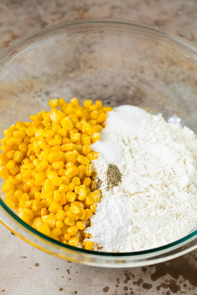 These crispy corn fritters are easy to make and are the perfect appetizer or lighter main course. #corn #fuyos Flour, corn and seasonings in a mixing bowl.