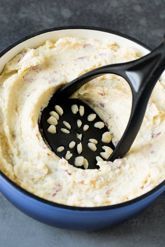 A potato masher in a pot of potatoes.