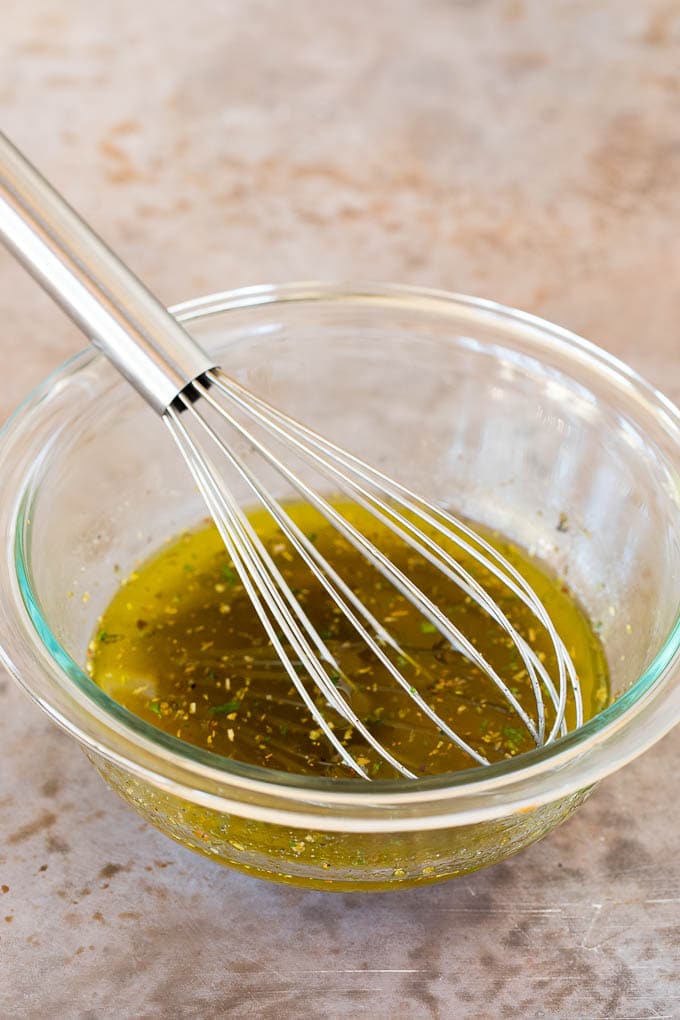 A bowl of homemade Italian dressing with a whisk in it.